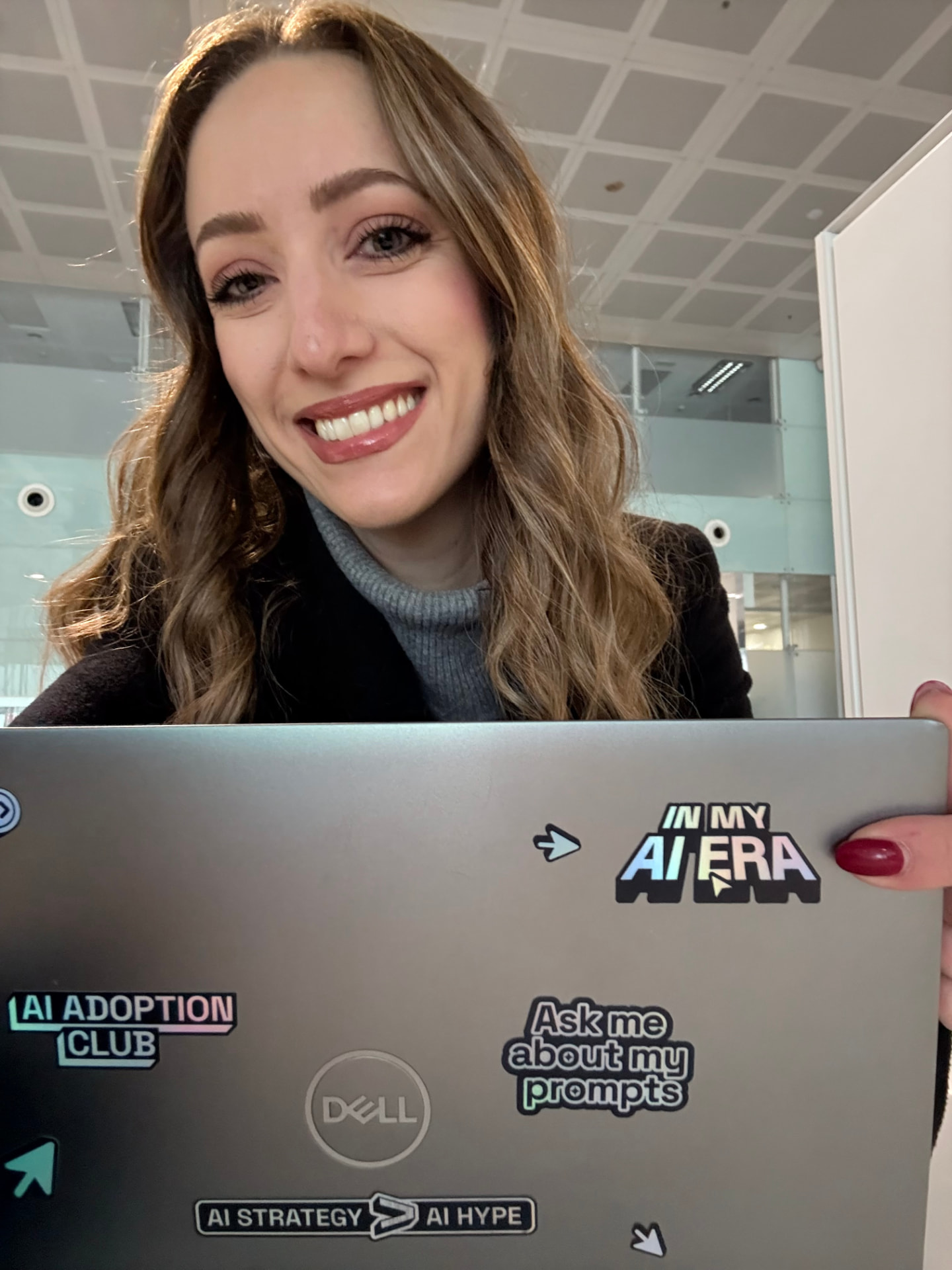 Dunja Stanivukovic working at a laptop covered in AI stickers